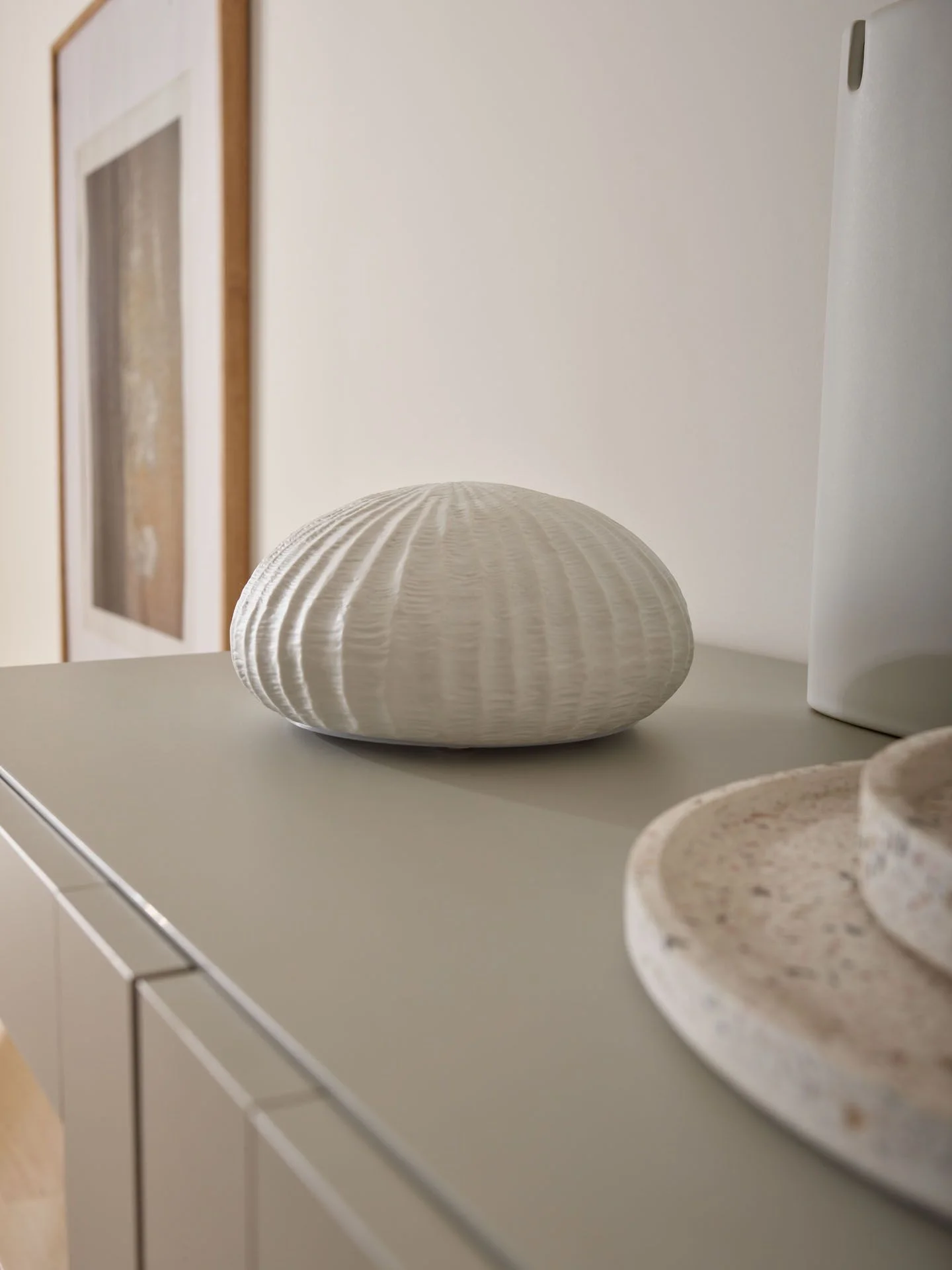 Biała dekoracja ceramiczna na beżowej komodzie.